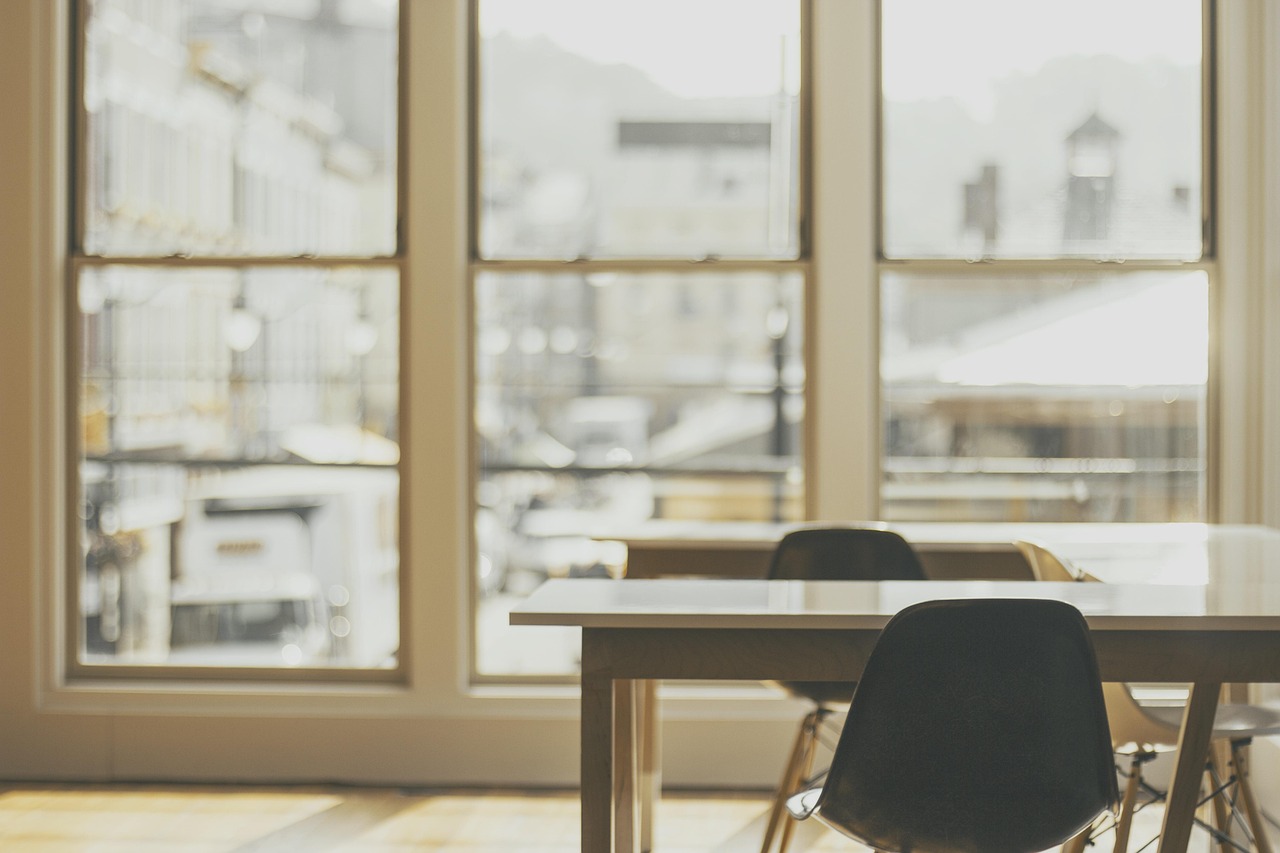 A quiet modern office with rows of empty desks and tall daylit windows